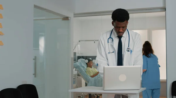 Médecin utilisant un ordinateur portable pour traiter le patient dans la salle d'hôpital — Photo