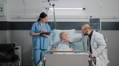 Hastane koğuşunda steteskoplu hasta bir hastaya danışmanlık yapan doktor.