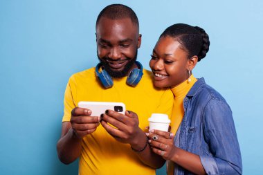 Neşeli çift eğlenmek için akıllı telefon ekranına bakıyor.