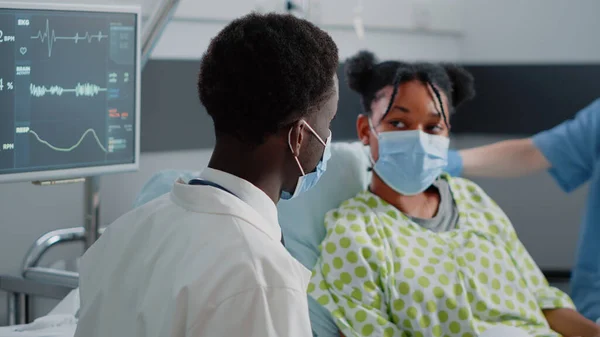 Close up of physician talking to young patient in bed — Stock Photo, Image