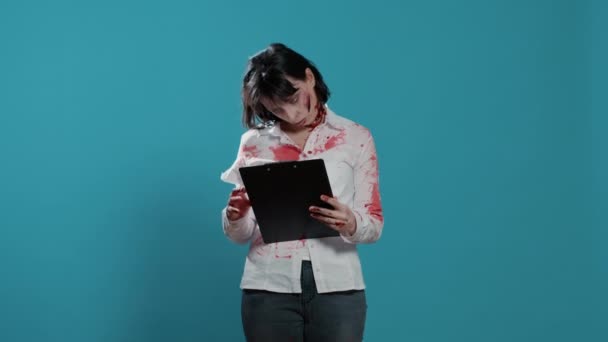 Dziwnie wyglądająca osoba ze schowkiem na dokumenty stojąca na niebieskim tle. — Wideo stockowe