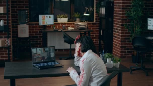 Zumbi escritório assustador irritado sentado na mesa enquanto gesticulando com raiva em chamada de vídeo digital. — Vídeo de Stock