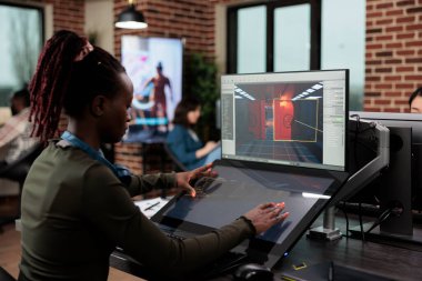 Oyun tasarımcısı ortam ve seviye ayrıntıları üzerinde çalışırken ofis çalışma alanında oturuyor.