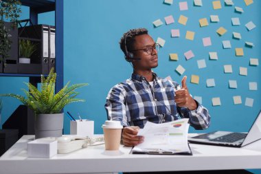 Yardım hattı operatörü kulaklık takıyor, onay işareti gösteriyor