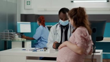 Genel pratisyen, hamile bir kadınla randevuda dijital tablet kullanıyor.