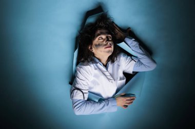 Aptal görünümlü ve dağınık saçlı çılgın kimyager mavi arka plan üzerinde başarısız bir deney yaptı. Tehlikeli kimyasal patlamadan sonra tuhaf saç stili ve kirli yüzü olan aptal bilim adamı..