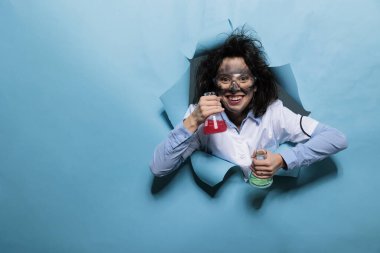 Kimyasal bileşiklerle dolu cam mataraları olan çılgın bilim adamı. Aptal yüz ifadesi olan çılgın bir kimyager kameraya bakarken deney amaçlı sıvı serumla dolu cam kavanozlar tutuyor..