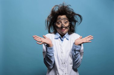 Çılgın görünümlü, dağınık saçlı, kirli yüzlü, kimyasal deney patlamasından sonra omuz silken çılgın bir kimyager. Aptal görünüşlü çılgın bilim adamı mavi arka planda omuzlarını silkiyor..