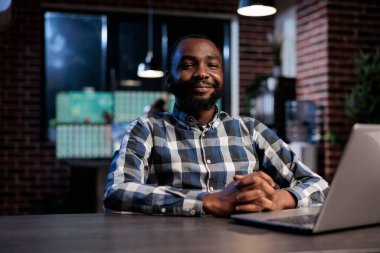 Ticaret ajansının eski borsa analisti kameraya gülümserken masada oturuyor. Yatırım ajansı kendinden emin ve profesyonel bir çalışan ofisinde oturuyor..