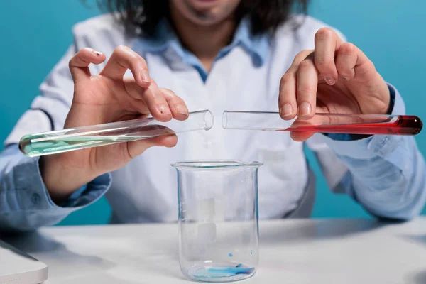 Close up of crazy silly biochemist using glass tubes to mix unstable chemical compounds while testing new formula. Mad foolish scientist testing experimental serum by adding unknown substance.