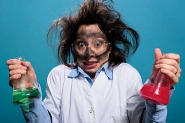 Puzzled crazy chemist having beakers filled with blood samples on blue background. Confused silly chemistry expert holding glass jars filled with toxic chemical liquid substances. clipart