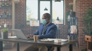İnternette web sitesi uygulaması kullanarak dizüstü bilgisayardaki veri raporunu analiz eden Afrikalı Amerikalı iş adamı. Ofis çalışanı, covid 19 salgını sırasında ağ üzerinde proje planlamak için araştırma yapıyor..