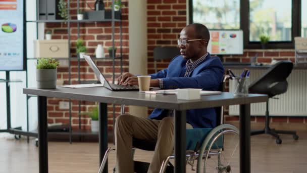 轮椅上瘫痪的员工使用笔记本电脑计划创业项目 在方便残疾人的办公室遭受慢性损伤和身体健康状况的折磨 三脚架射击 — 图库视频影像