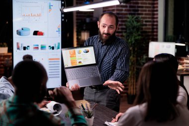 Gece geç saatlerde iş analizleriyle birlikte iş arkadaşlarıyla iş görüşmesi yapan pazarlama müdürü. Girişimci çeşitli takımlarla satış istatistikleri hakkında konuşuyor.