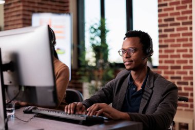 Tekerlekli sandalye kullanıcısı ve resepsiyonist yardım hattında çalışıyor, maluliyet dostu ofiste müşterilere yardım ediyor. Kronik sağlık durumu ve yetersizlik ile yaşayan müşteri hizmetleri çalışanı.