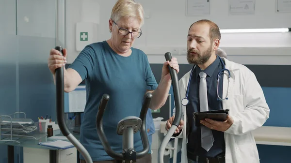 Чоловік Лікар Вивчає Старшу Жінку Стаціонарному Велосипеді Допомагаючи Альтернативною Медициною — стокове фото