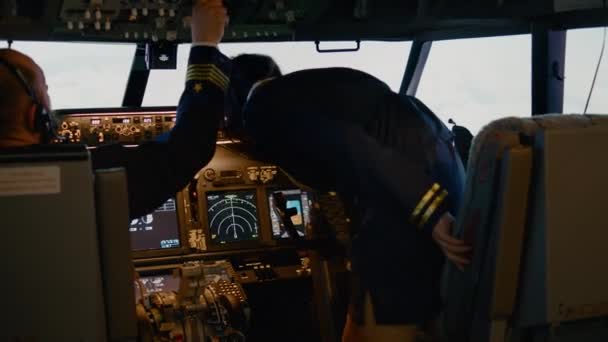 機長と女性の副操縦士のチームは コックピット内のコントロールパネルダッシュボードで飛行機を飛行する高度と経度を固定します エンジンを回転させ ナビゲーションコンパスで離陸する 手持ち撮影 — ストック動画