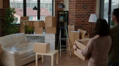 Çeşitli evli çiftler, ev kredisi ve ipotekle satın alıyor, emlak işlerine birlikte giriyorlar. Yeni aile başlangıçları için oturma odası mobilyalarını açmak için karton paketler.