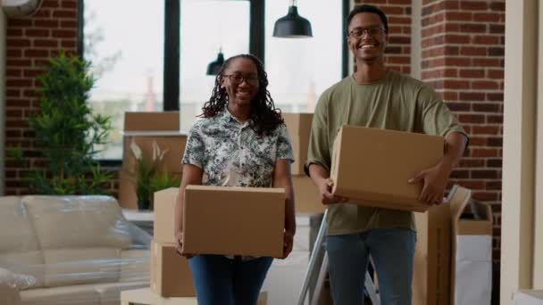 非洲裔美国夫妇在抵押贷款购买公寓后一起搬进来的肖像 看着相机 对搬迁感到高兴 纸板箱搬家具 — 图库视频影像