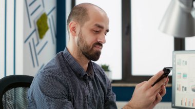 İnterneti taramak için akıllı telefona bakan bir işadamı pazarlama büyümesini planlamak için satış istatistikleriyle çalışıyor. Cep telefonuyla çalışan mali uzmanlık sahibi bir erkek..