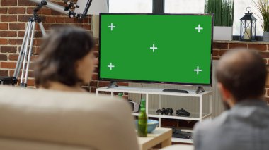 Kanepede oturan gençler yeşil ekran ile televizyona bakıyor, arka planda izole edilmiş krom anahtar şablonu izliyorlar. Televizyondaki boş fotokopi alanını kullanan arkadaşlar. Kapat..