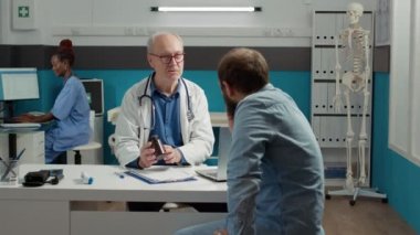Sağlık uzmanı, kabinedeki hastaya reçeteli ilaç şişesi göstererek hastalık tedavisini açıklıyor. Sağlık hastalıklarını tedavi etmek için ağrı kesici, ilaç ve ilaç şişesi..