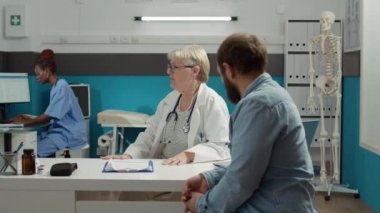 Kadın doktor, röntgen taraması sonuçlarını hastaya veriyor. Kemik hastalıklarını açıklıyor. Hastalığı reçeteli ilaç ve tedaviyle tedavi etmek için radyografinin analizi.