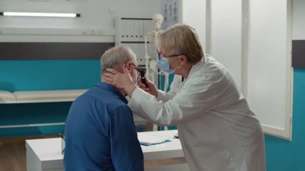 Médico Mediante Otoscopio Para Realizar Examen Oído Consultando Paciente Anciano — Vídeos de Stock