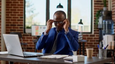 Erkek danışman, başlangıç ofisinde iş stratejisi geliştirmek için evrak işleriyle uğraşıyor. Proje yöneticisi dizüstü bilgisayardaki çevrimiçi istatistikleri analiz ediyor, internet web sitesi raporlarına bakıyor. Üçayak atışı.