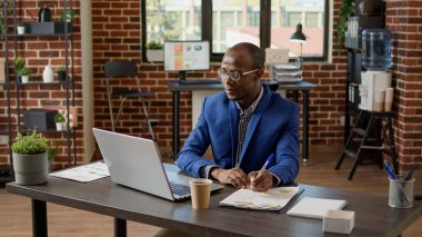 Afrikalı Amerikalı adam şirket ofisinde internet kamerasından konuşuyor, internet konferansında müdürle konuşuyor. Telework iletişimi için uzak video telekonferans toplantısı.