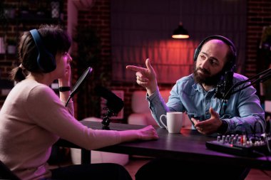 Erkek sunucu, podcast 'te bir kadınla röportaj yapıyor. Stüdyoda konuklarla konuşuyor. Genç adam sosyal medya blogcusu ile sohbet ediyor, kanal içeriği için kayıt yapıyor.