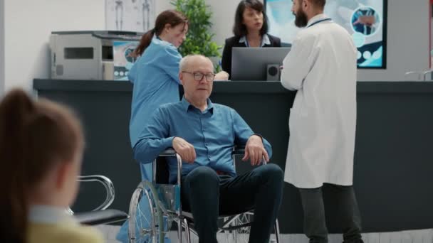 老年人轮椅使用者在医院接待处候车室区的画像 有残疾和健康问题的退休男子 在设施前厅处理慢性残疾问题 — 图库视频影像