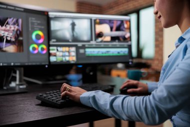 Uzman yazılım kullanarak film görüntülerini geliştirirken profesyonel kameramanların masa başında oturduğu yakın çekim. Yaratıcı film editörü, çoklu monitör çalışma istasyonunda oturuyor..
