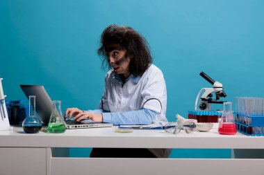 Çılgın çılgın kimyager laboratuvarda masasında oturmuş laptoptaki başarısız deney raporlarını analiz ediyor. Çatlak görünüşlü manyak bir bilim adamı. Kimyasal bileşikleri analiz etmek için bilgisayar kullanıyor..