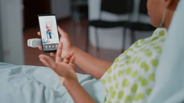 Close up of patient holding smartphone with video call, having remote consultation with doctor about healthcare and recovery. Woman using online conference, telemedicine and telehealth