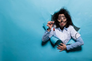 Garip görünüşlü deli bir kimyager laboratuvarda tehlikeli kimyasal patlamadan sonra kan örneğiyle dolu bir test tüpü tutuyor. Çılgın biyokimya uzmanının cam matarası var.