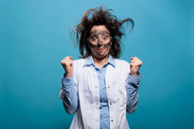 Dağınık saçlı ve yüzlü çılgın kimyager başarısız bilimsel deney için üzülürken öfkeyle yumruklarını sıkıyor. Korkunç saç stili ve kirli yüzüyle sinirli kaçık bir bilim adamı..