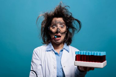 Dağınık saçlı ve kirli yüzlü çılgın bilim adamının dişlerinin arasında bilinmeyen kırmızı sıvı maddeyle dolu cam test tüpü var. Laboratuvardaki kimyasal patlamadan sonra kafası karışmış çılgın kimyager..