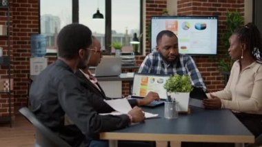 Yeni sunum analizi hakkında fikir alışverişinde bulunmak için toplantı odasında toplanan Afrikalı Amerikalılar. İş arkadaşları strateji planlamak için takım çalışması yapıyor.