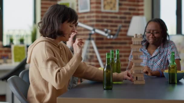 年轻女子用木片撞毁了大楼塔台 输掉了棋盘比赛 人和快乐的朋友在聚会上玩方块方块游戏 — 图库视频影像