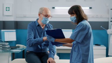 Kıdemli doktor, kovid 19 salgını sırasında sağlık hemşiresine muayene kağıtlarını imzalıyor. Hasta iyileşme ve rehabilitasyon için yardım ve destek almak için dosyaları imzalıyor.