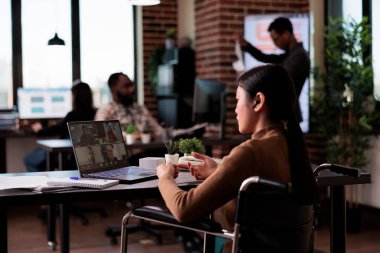 Fiziksel engelli çalışan engelli bürosundaki video konferansına katılıyor, çevrimiçi video konferansında insanlarla sohbet ediyor. Tekerlekli sandalye kullanıcısı uzaktan telekonferansta konuşuyor.