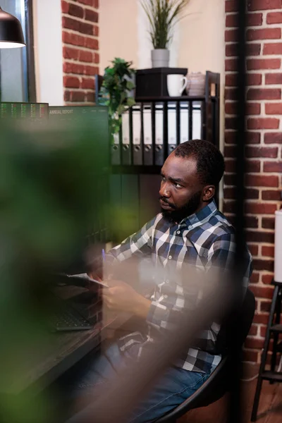 Hedge fund trader analyzing market trend while sitting at workstation having documentation clipboard. Trading analyist monitoring real time financial data to predict next price crash.