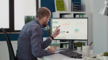 Şirket muhasebecisi, ticari strateji planlamak için e-ticaret istatistiklerini kullanarak bilgisayar monitöründeki iş haritalarını ve satış verilerini analiz ediyor. Proje geliştirme üzerinde çalışan erkek çalışan.