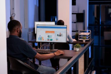 Ofis çalışanı bilgisayar yazılımı ile ilgili iş bilgilerini analiz ediyor, proje ve sunumu planlamak için istatistik ve veri araştırmalarıyla çalışıyor. Monitörde grafiklerle rapor oluşturuluyor.
