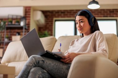 Asyalı kadın evde online film seyrediyor abonelik platformu, eğlence filmi dizisi internet teknolojisi dizisi dizüstü bilgisayarda yeni medya dijital uygulaması yayınlıyor