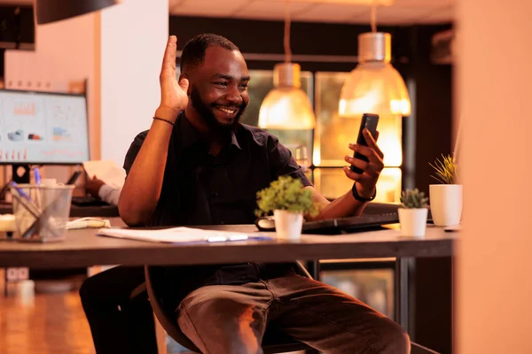 Afrikalı Amerikalı bir adam akıllı telefondan video konferans kullanıyor. İnternetteki telekonferansta iş arkadaşlarıyla uzaktan sohbet ediyor. Web kamerasıyla internet görüntülü konferans görüşmesi..