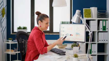 Finans analisti internet sitesini taramak için akıllı telefon kullanıyor, şirket ofisinde çalışıyor. Çalışan cep telefonu ekranına bakıyor ve ekonomik veri araştırması yapıyor, çevrimiçi analiz.