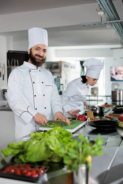 Mutfakta garnitür hazırlarken gülümseyen baş aşçı gastronomik yemekler pişiriyor. Gurme mutfak şefi taze sebzeleri keserken yemek için yemek tarifi hazırlıyor..