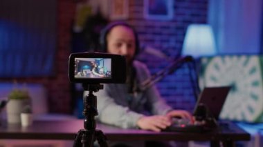Seçici odak noktası dijital video kamera kayıt etkileyicisi beyaz adam canlı talk show 'u ev stüdyosundan mikrofon kullanarak yayınlıyor. Sosyal medya paylaşımı için vlog kaydeden erkek içeriği oluşturucu.
